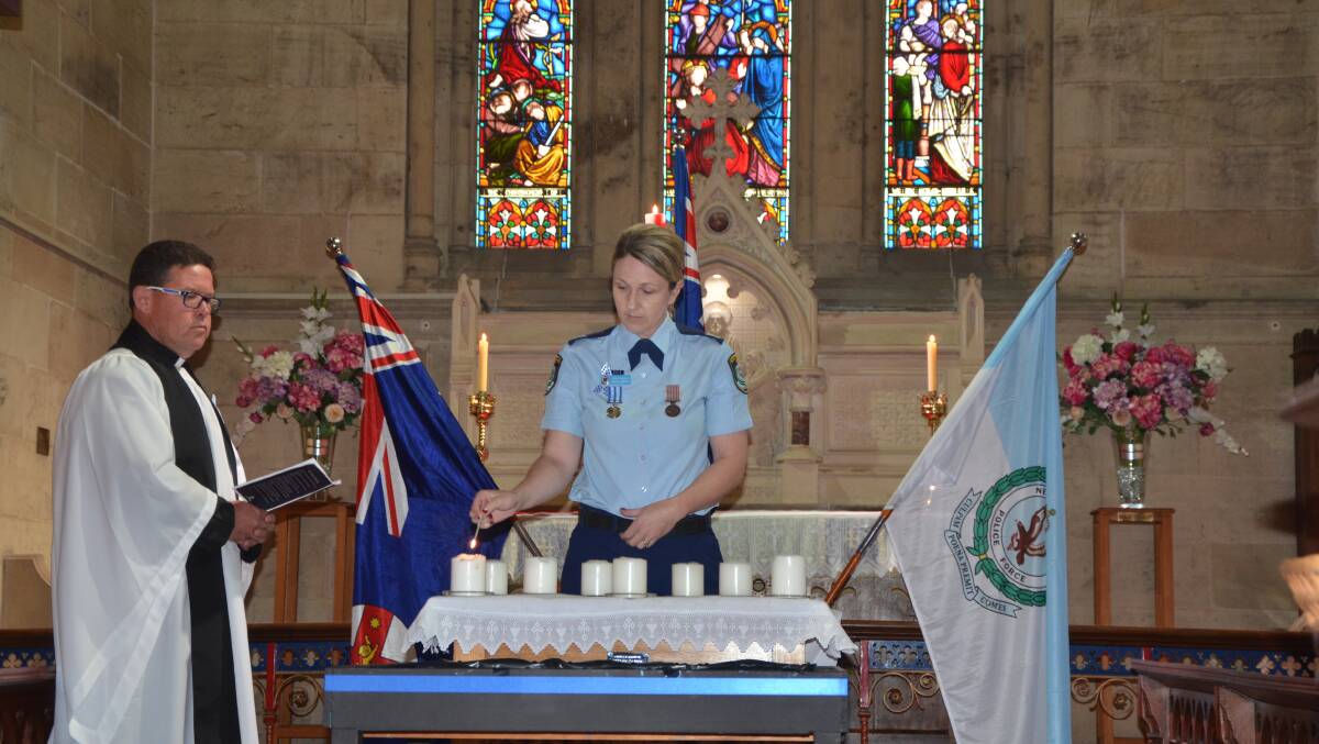 HONOUR: Hunter Valley Local Area Command Senior Constable Kylie Smith lights a candle during a National Police Remembrance Day ceremony at St Alban’s Anglican Church on Thursday.