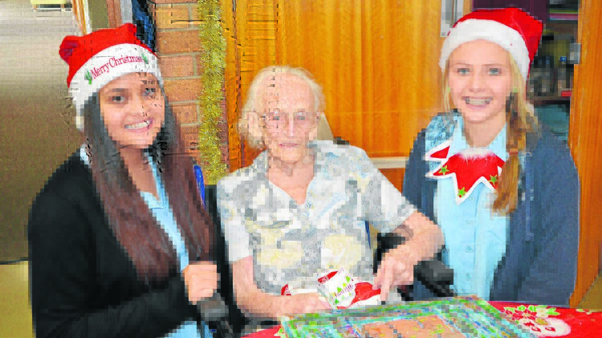 Scone High School students Gabrielle Vickers and Rachael Tillemans delivering a gift to Strathearn resident Ivy Palmer (centre).

