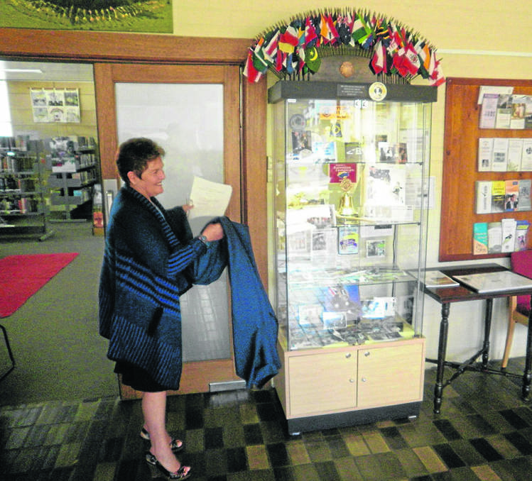 Murrurundi Lions Club president Lynne Mahony unveiling the showcase cabinet donated to Murrurundi Library recently.