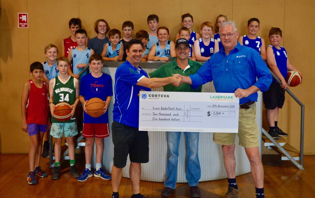 Scone Basketball Association president Earl Burnett accepts a grant from Mick Seale of Landmark Scone and Corteva Agriscience Key Account Manager Jon Dadd. 