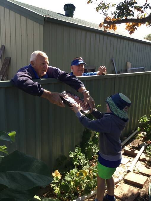 SHARING: David Spencer from the Upper Hunter Men's Shed hands over the sausages. Photo: supplied