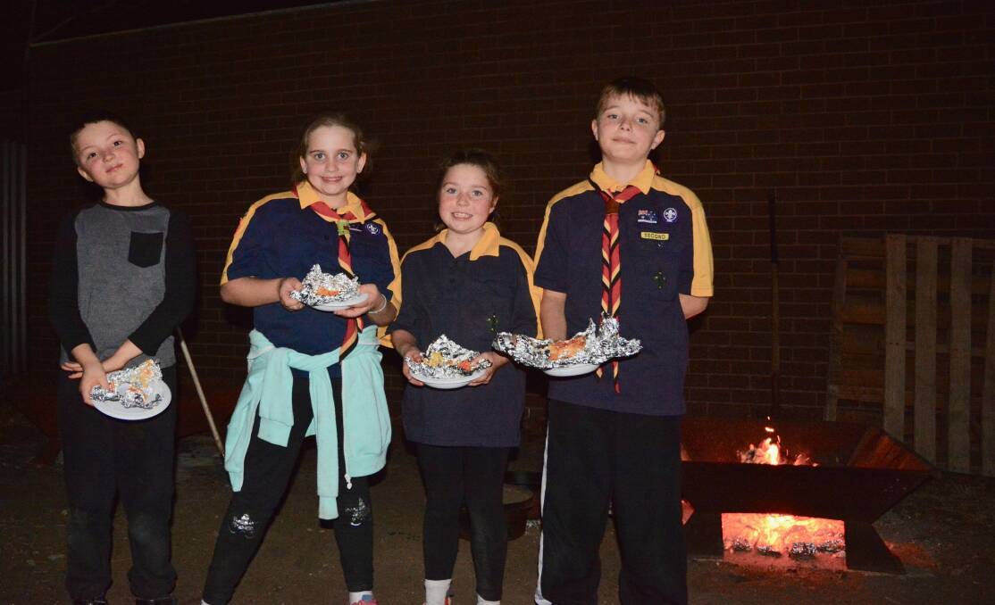 DINNER TIME: James, Mollie, Jasmine and Toby enjoyed a dinner cooked under the camp fire at Cubs' weekly meeting on Monday. 