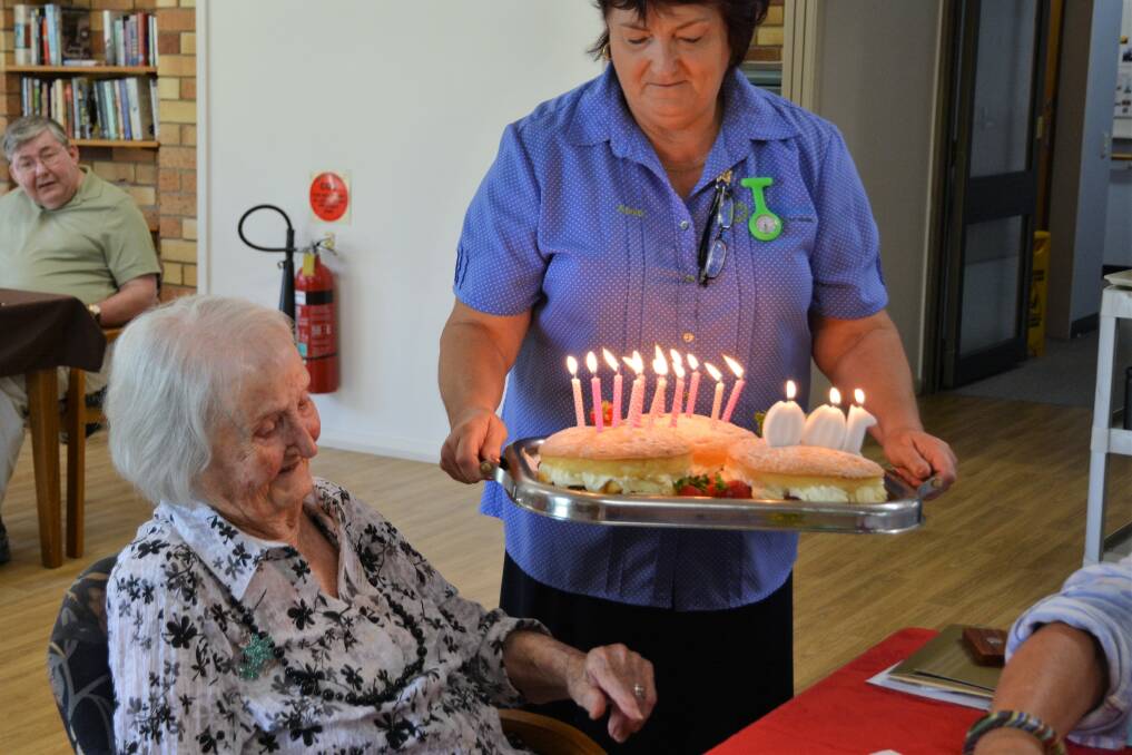 MILESTONE: Activities Officer at Strathearn Anne Meier presents Mab Ryan with her birthday cake to celebrate 100 years. 