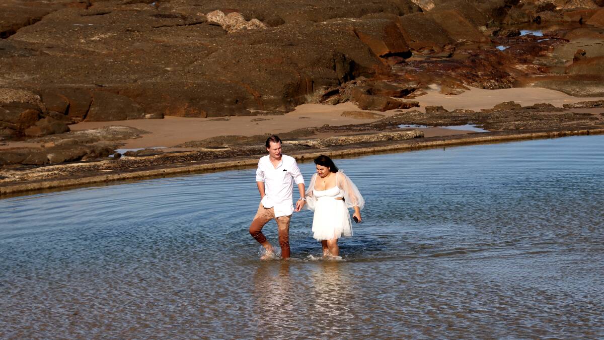 Just two hours after Grant and Andrea Goodlet were married, it was off with the shoes for a bit of fun at the Newcastle Ocean Baths toddlers pool. Picture by Peter Lorimer 