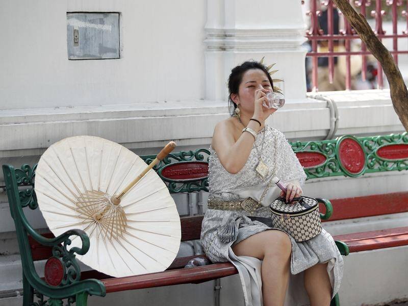 A tourist drinks water during hot weather at the Temple of Dawn or Wat Arun in Bangkok. (EPA PHOTO)